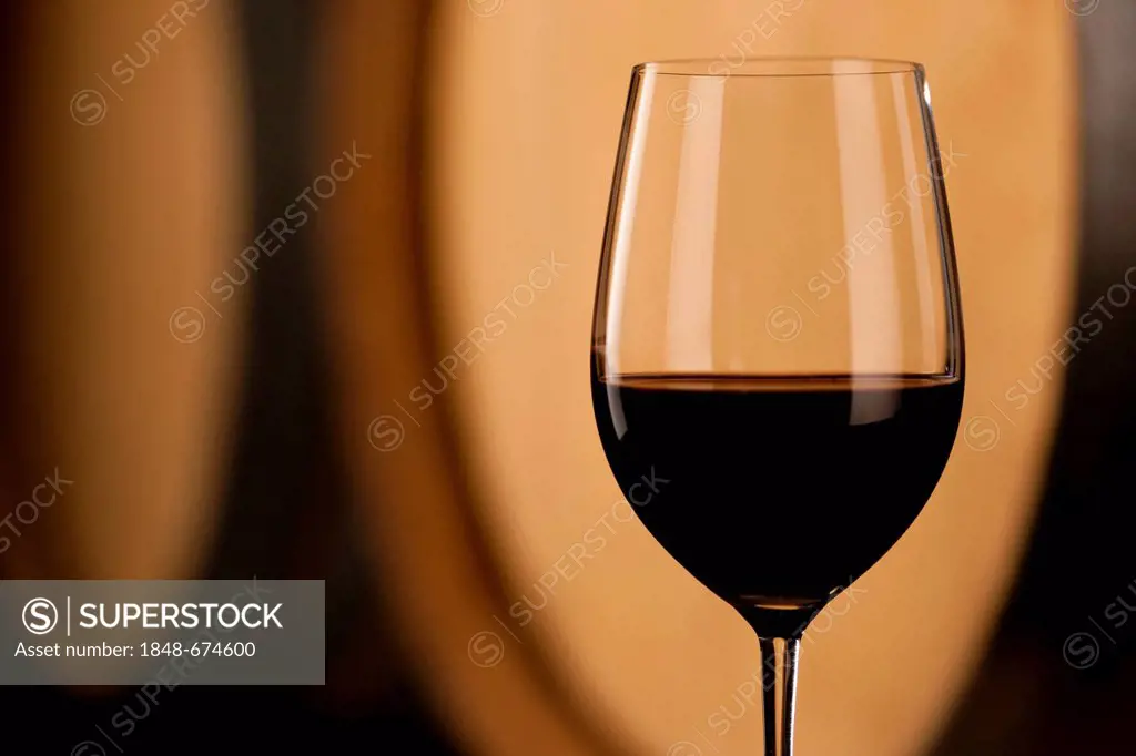 Wine glass in front of wine barrel