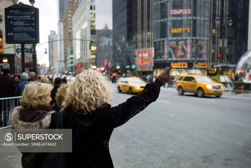 Women trying to hail a yellow cab, New York, USA