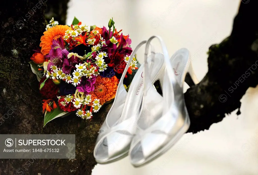 Bridal bouquet and silver wedding shoes hanging from a tree