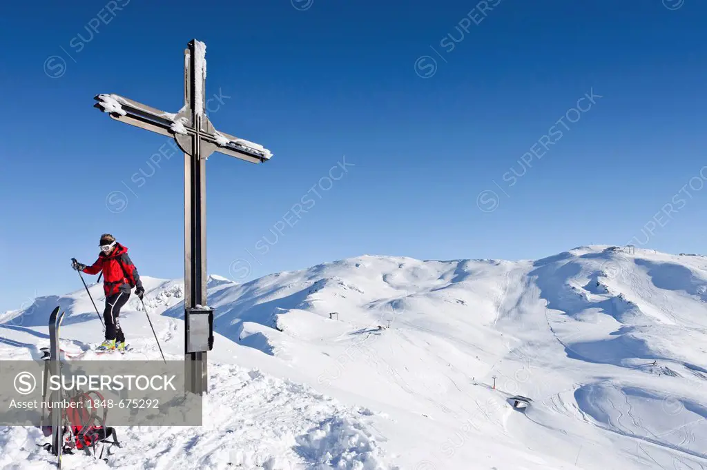 Snowshoe walker at the summit cross of Morgenrast mountain above Unterreinswald, Sarntal valley, Reinswald skiing area the back, province of Bolzano-B...