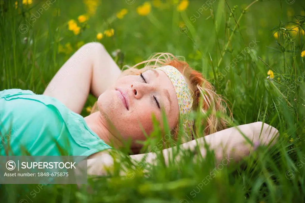 Young woman lying on a flowery meadow