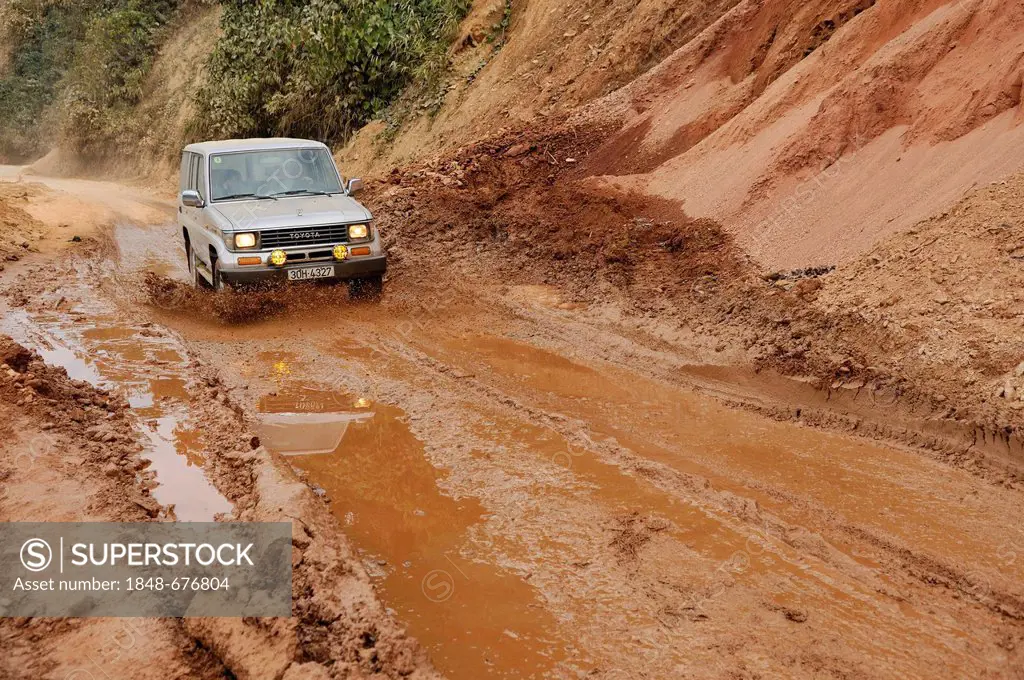 Toyota Land Cruiser driving on a muddy road through puddles, Vietnam, Asia