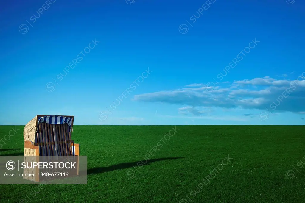 Roofed wicker beach chair on a green lawn for sunbathing in front of a blue sky, North Sea coast, Germany, Europe