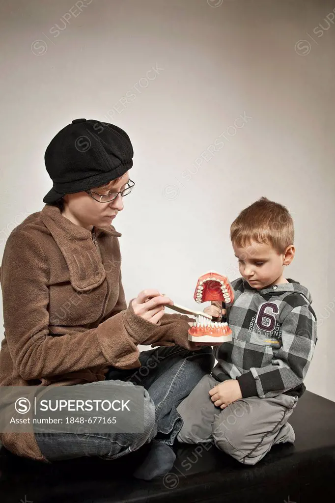 Boy learning how to brush his teeth, dental care lesson