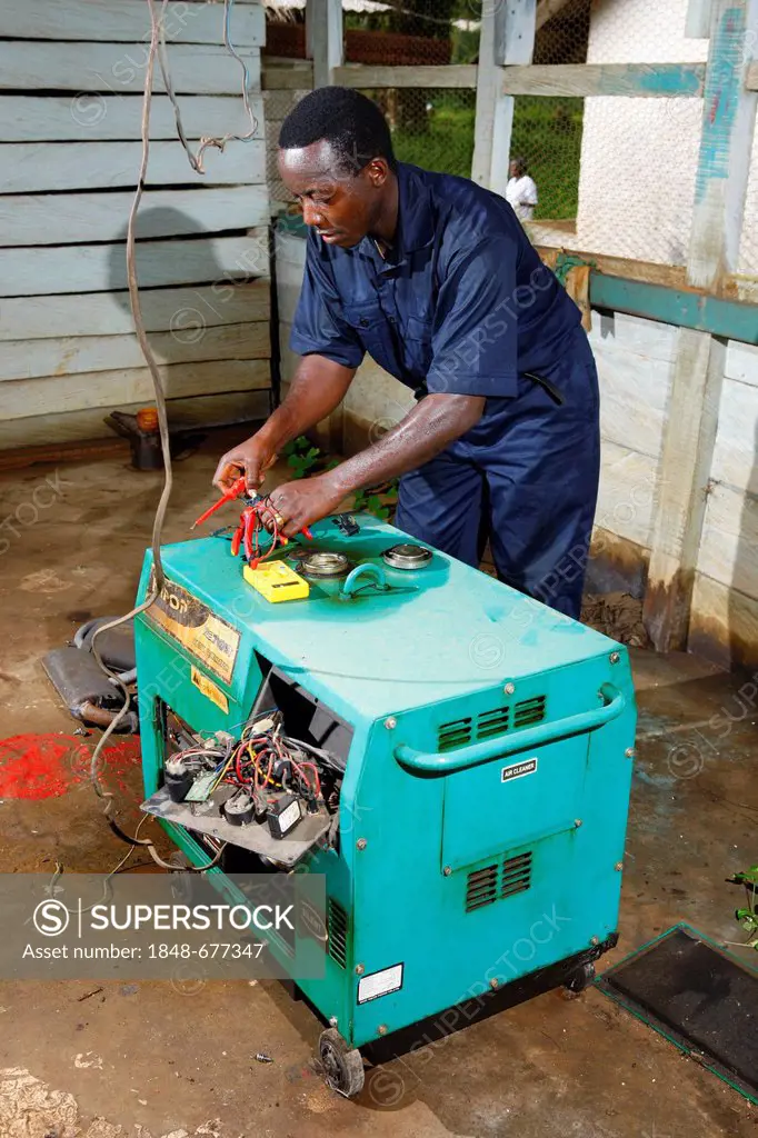 Mechanic repairing an emergency power generator, hospital, Manyemen, Cameroon, Africa