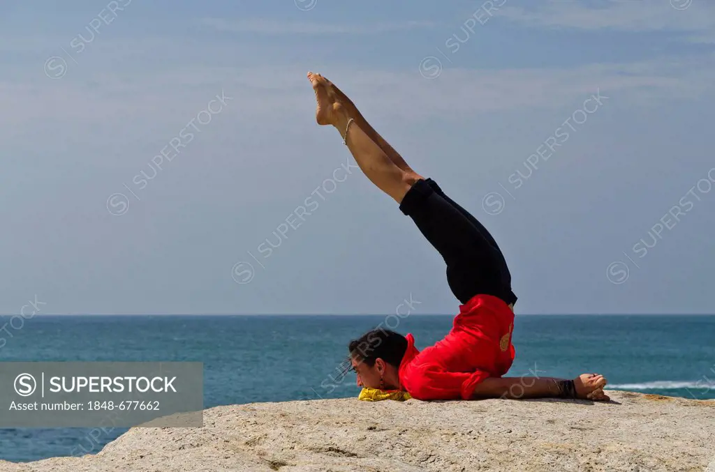 Woman in a yoga position, Salabhasana, by the sea in Kanyakumari, Tamil Nadu, India, Asia