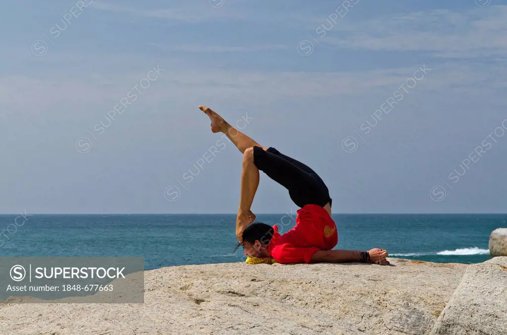 Woman in a yoga position, Salabhasana, by the sea in Kanyakumari, Tamil Nadu, India, Asia