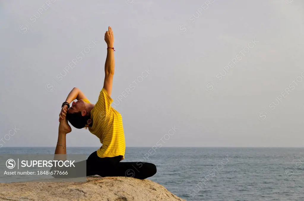 Woman in a yoga position, Kapotasana, by the sea in Kanyakumari, Tamil Nadu, India, Asia