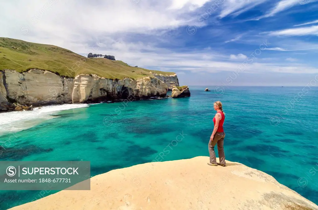 Woman standing on a cliff face, cliffs at Tunnel Beach near Dunedin, South Island, New Zealand, Oceania