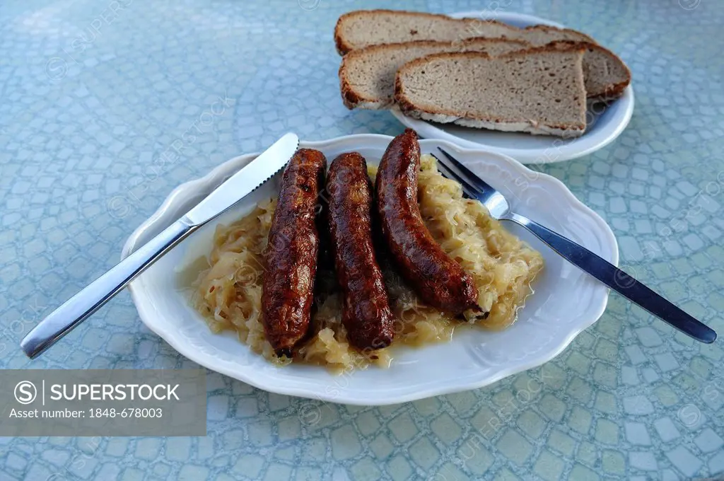 Three Franconian bratwurst sausages with sauerkraut and bread on a plate on a tavern table, Regensberg, Upper Franconia, Bavaria, Germany, Europe