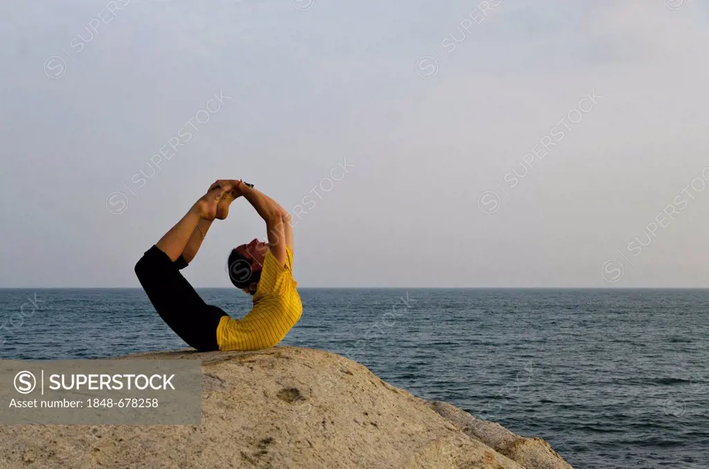 Woman in a yoga position, Dhanurasana, by the sea in Kanyakumari, Tamil Nadu, India, Asia