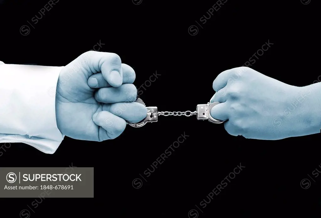 Two fists joined by miniature handcuffs, symbilic image for marriage