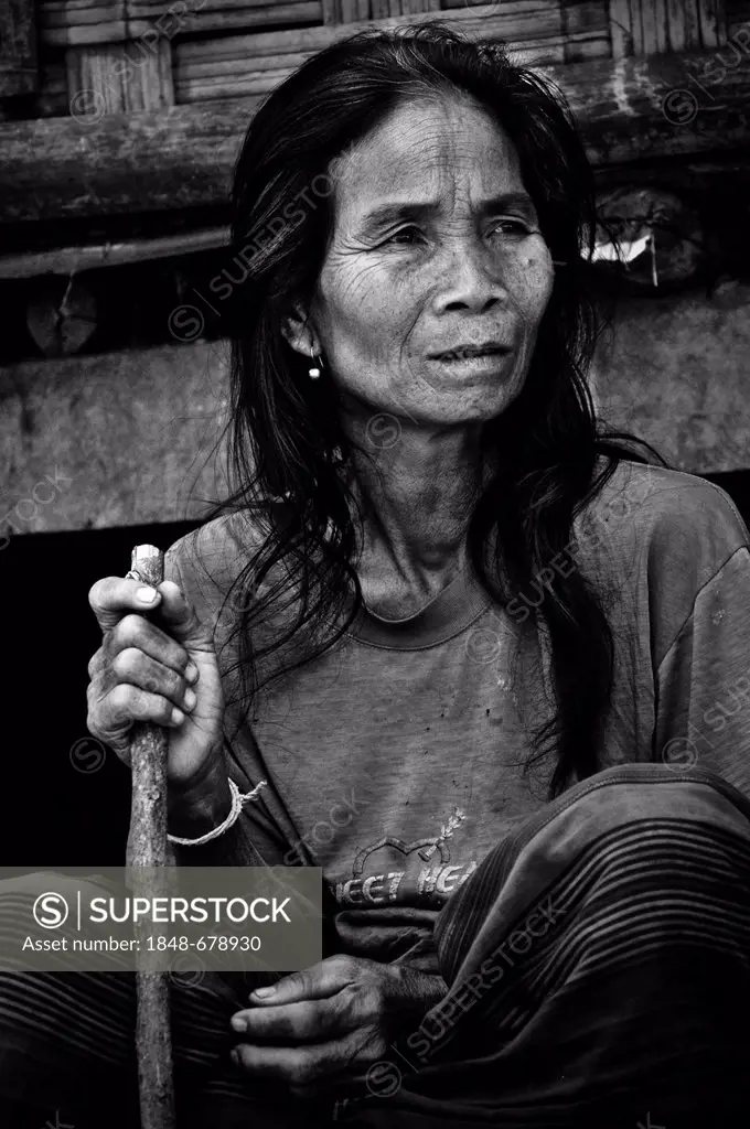 Old woman with a stick sitting in front of a bamboo hut, in a village on the Mekong River, Laos, Southeast Asia, Asia