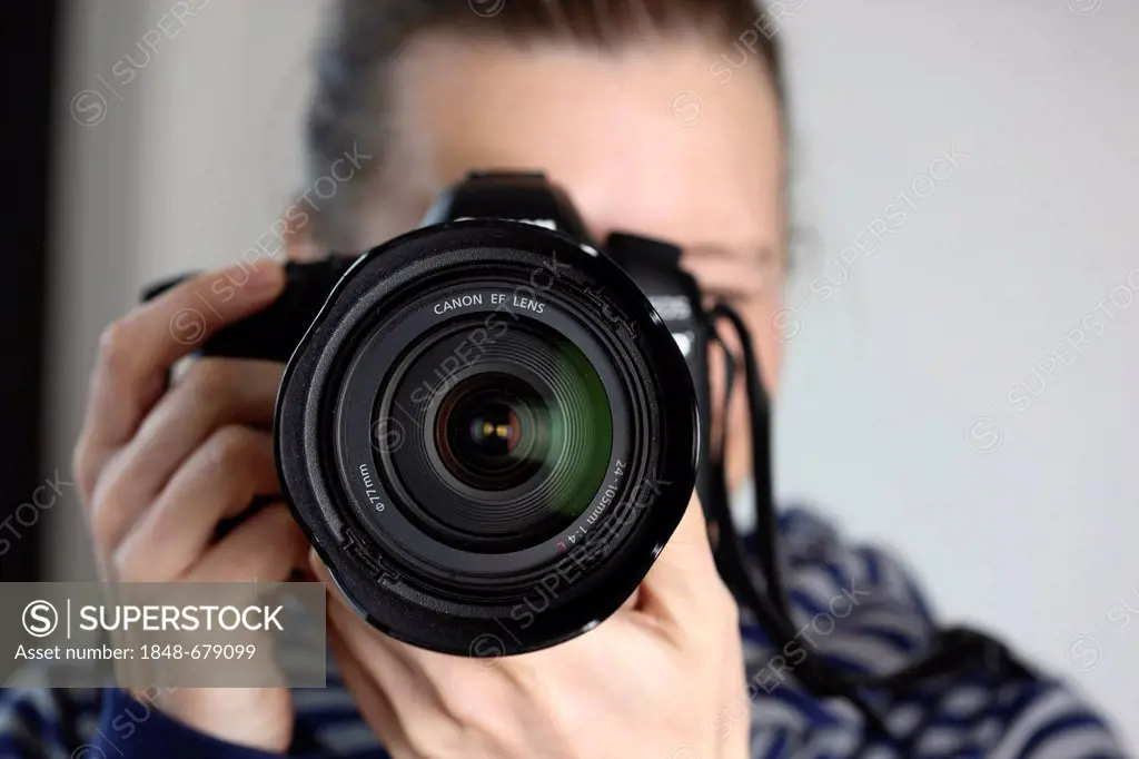 Woman looking through the viewfinder of a digital SLR camera