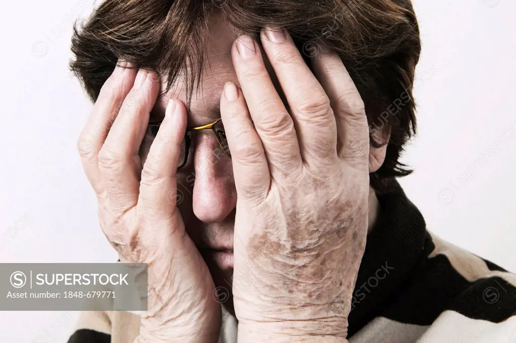Elderly woman looking distressed and holding her hands over her face