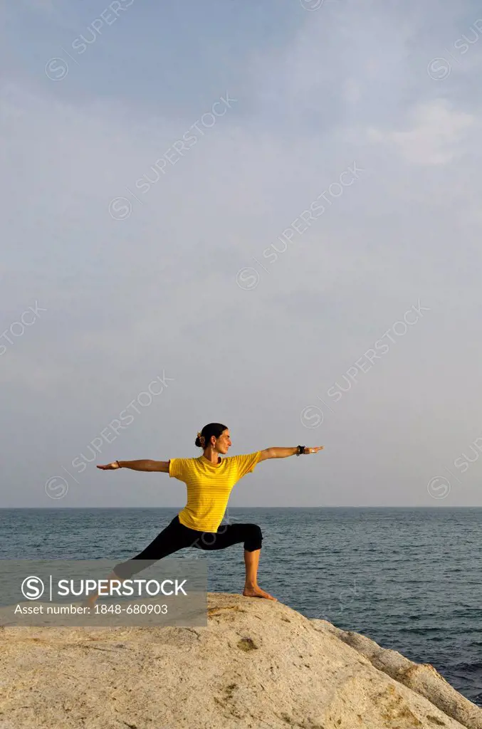 Woman in a yoga position, Virabhadrasana, by the sea in Kanyakumari, Tamil Nadu, India, Asia