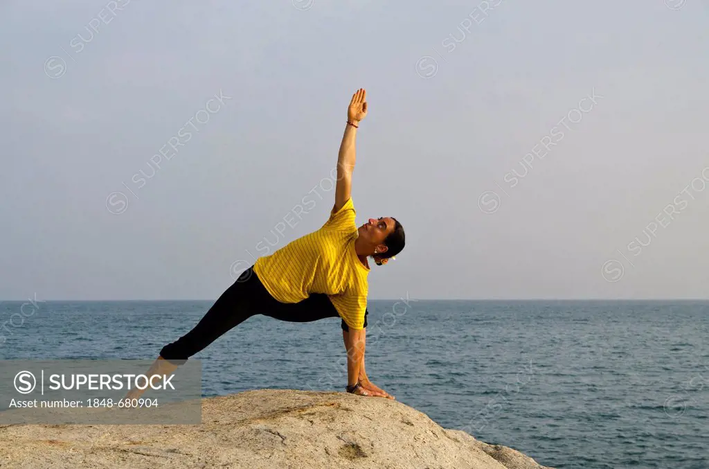Woman in a yoga position, Utthita-Parshvakonasana, by the sea in Kanyakumari, Tamil Nadu, India, Asia