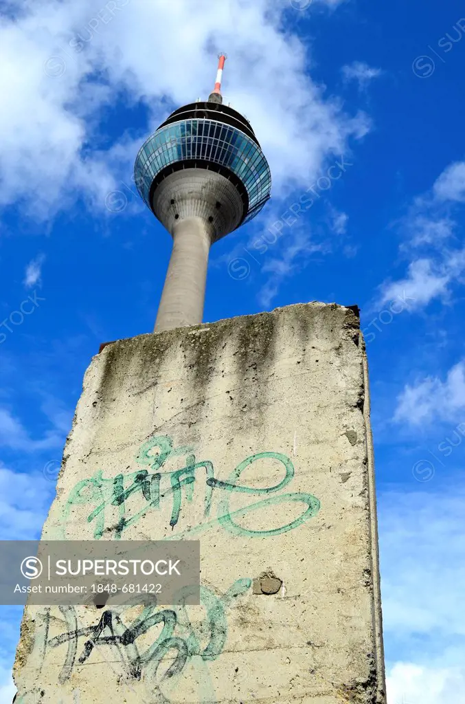 A piece of the Berlin Wall in front of the Rheinturm tower, Duesseldorf, North Rhine-Westphalia, Germany, Europe