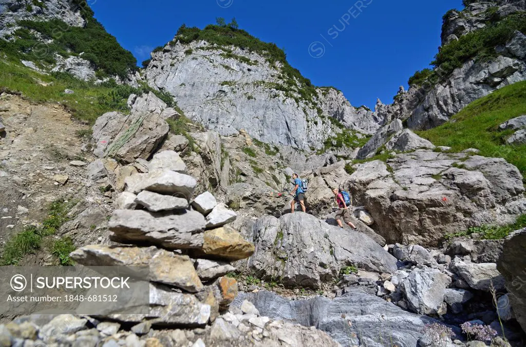 Hikers climbing a mountain, descending passt Klamml, on the way to Gruttenhuette mountain lodge, Ellmauer Halt, Wilder Kaiser mountain, Tyrol, Austria...