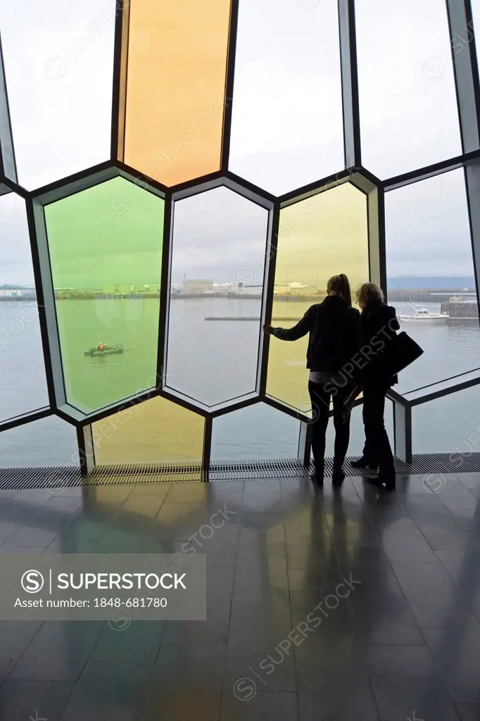 Visitors looking through the honeycomb-shaped windows in the facade, new Harpa concert hall in Reykjavik, Iceland, Europe