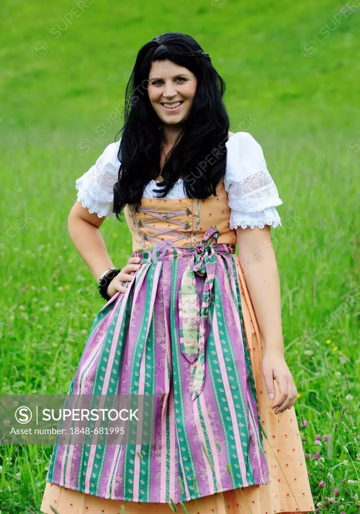 Smiling woman wearing a dirndl dress, standing in a meadow in Tyrol, Austria, Europe