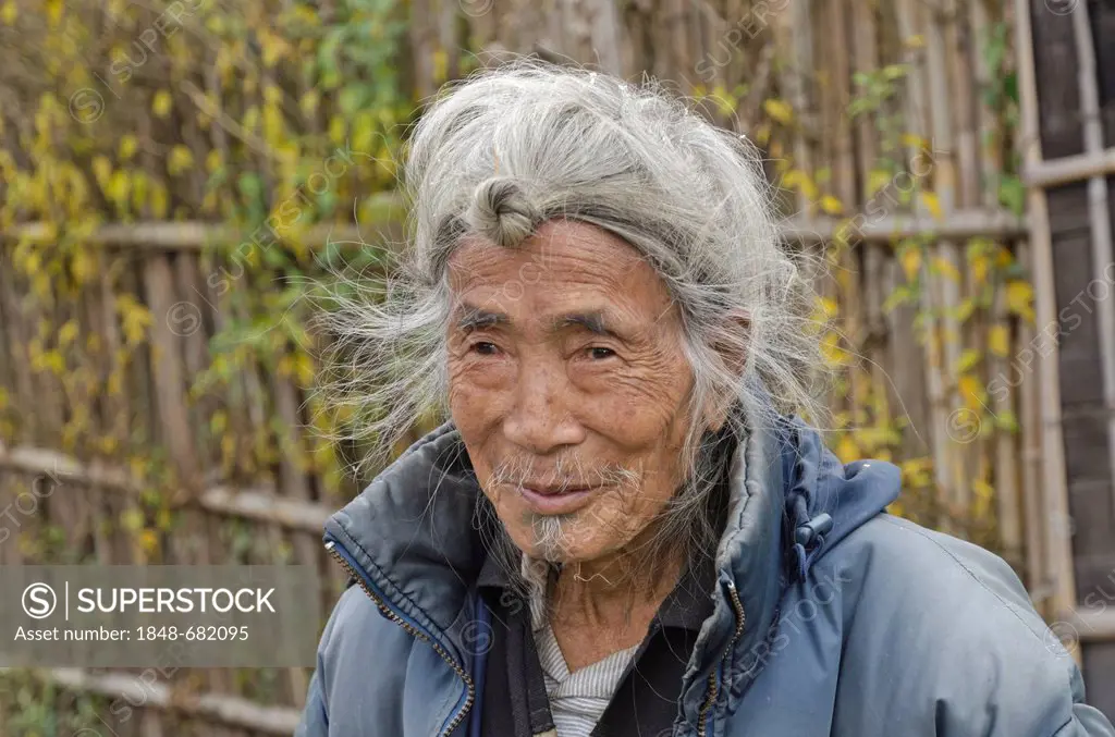 An old Apatani man with the traditional hairstyle with the knot at his forehead, Hong village in the hills of the Ziro area, Arunachal Pradesh, India,...