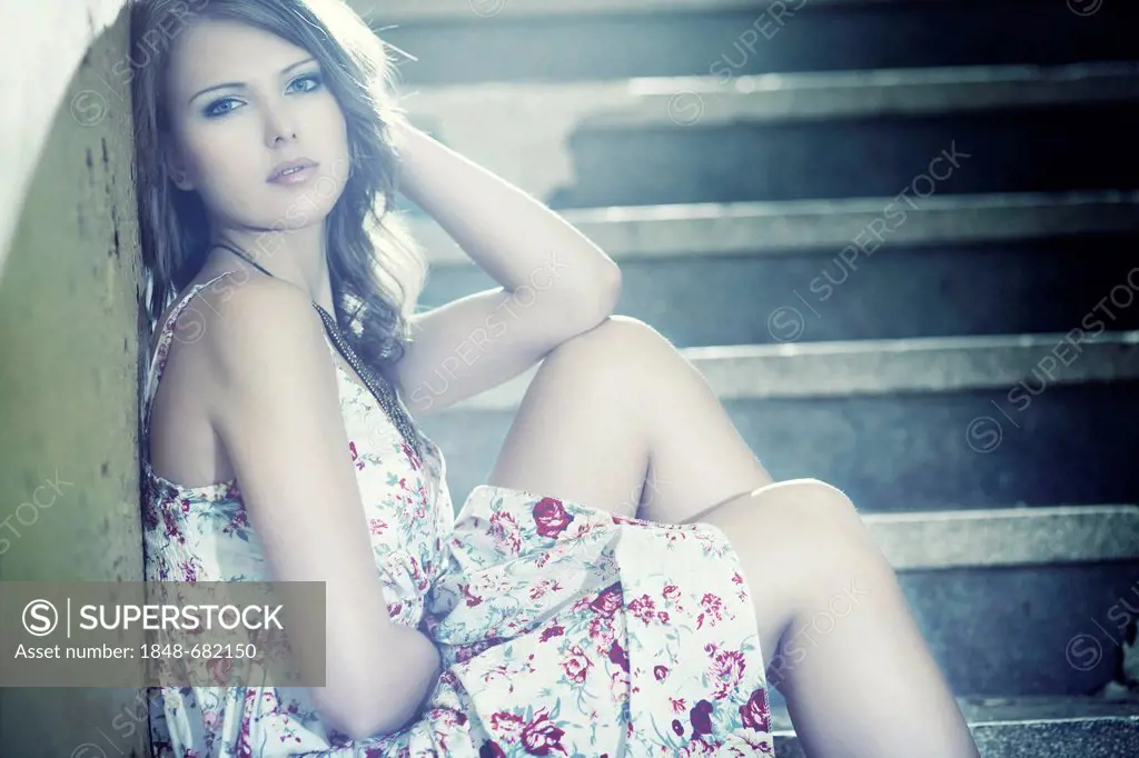 Young woman wearing a summer dress sitting on a staircase