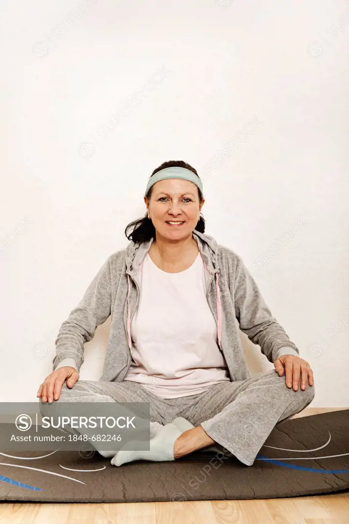 Woman sitting cross-legged on an exercise mat, yoga, gymnastics