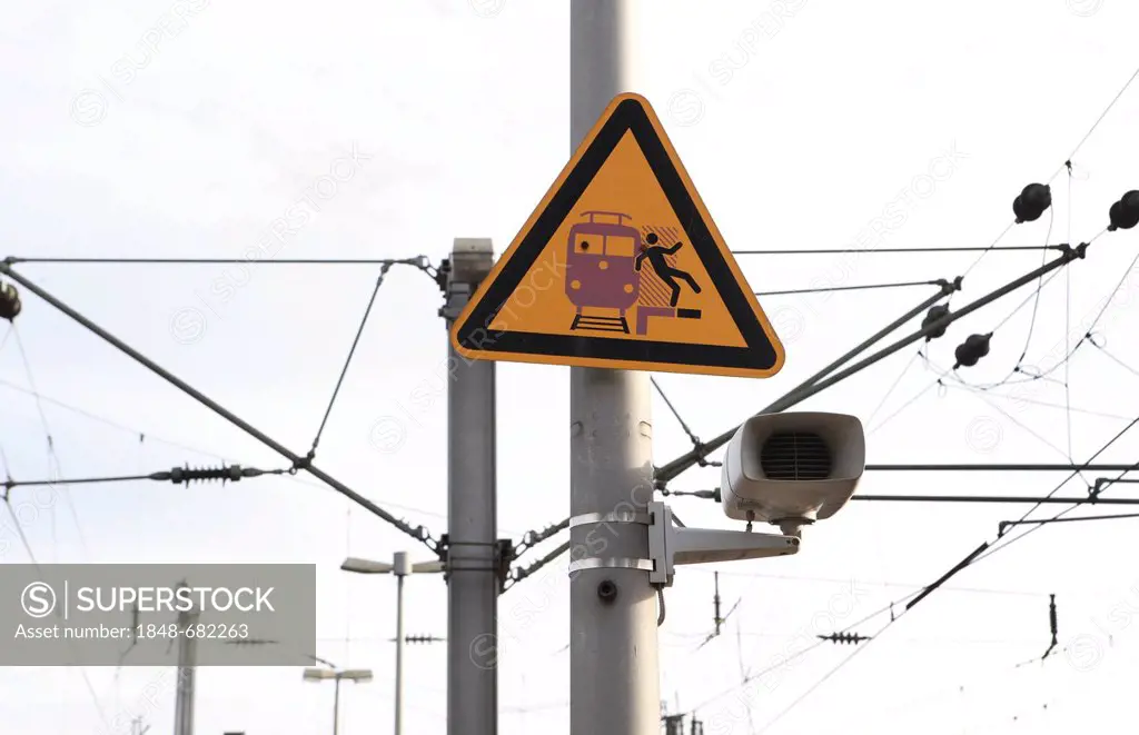 Speaker, overhead lines and a warning sign on a railway station