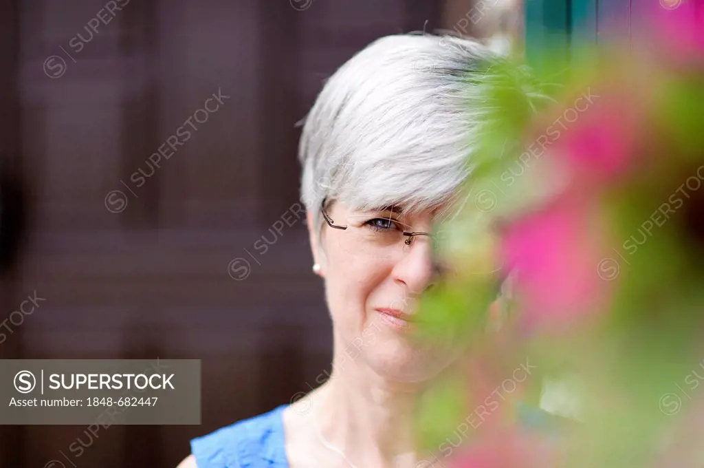 Woman looking out from behind a flowering bush