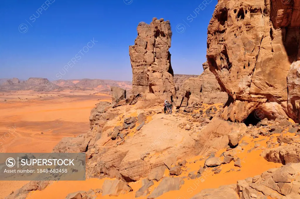 People hiking in a sandstone rock formation, Tadrart, Tassili n'Ajjer National Park, Unesco World Heritage Site, Algeria, Sahara, North Africa