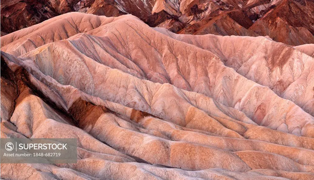 View from Zabriskie Point towards eroded rock formations discoloured by minerals, dawn, Death Valley National Park, Mojave Desert, California, United ...