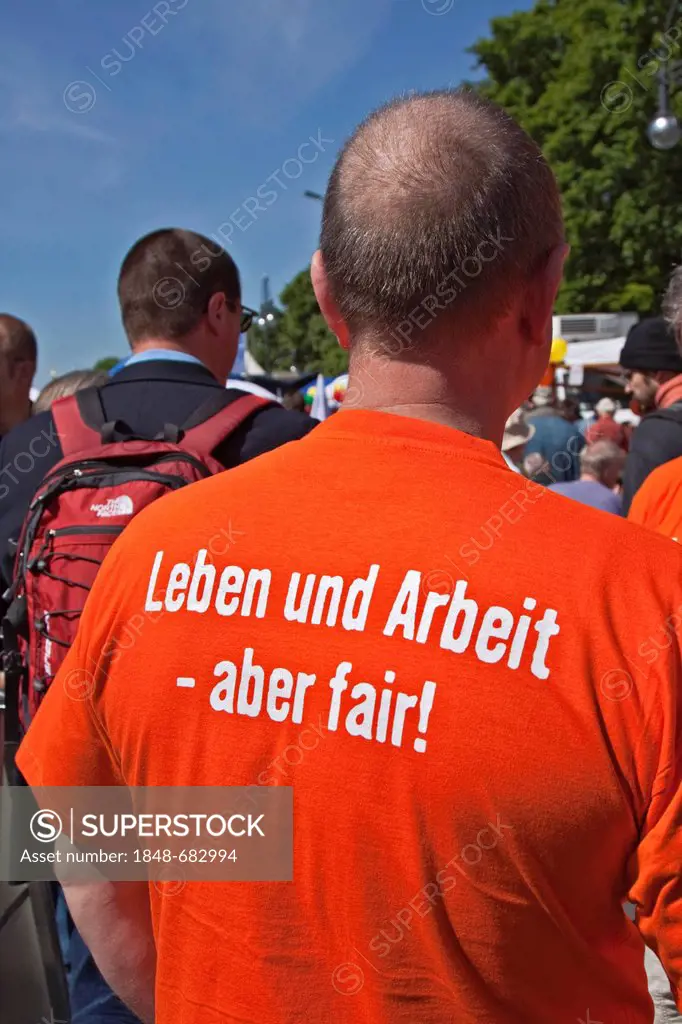 Writing Leben und Arbeit - aber fair! or life and work - but fair! on the back of an orange T-shirt