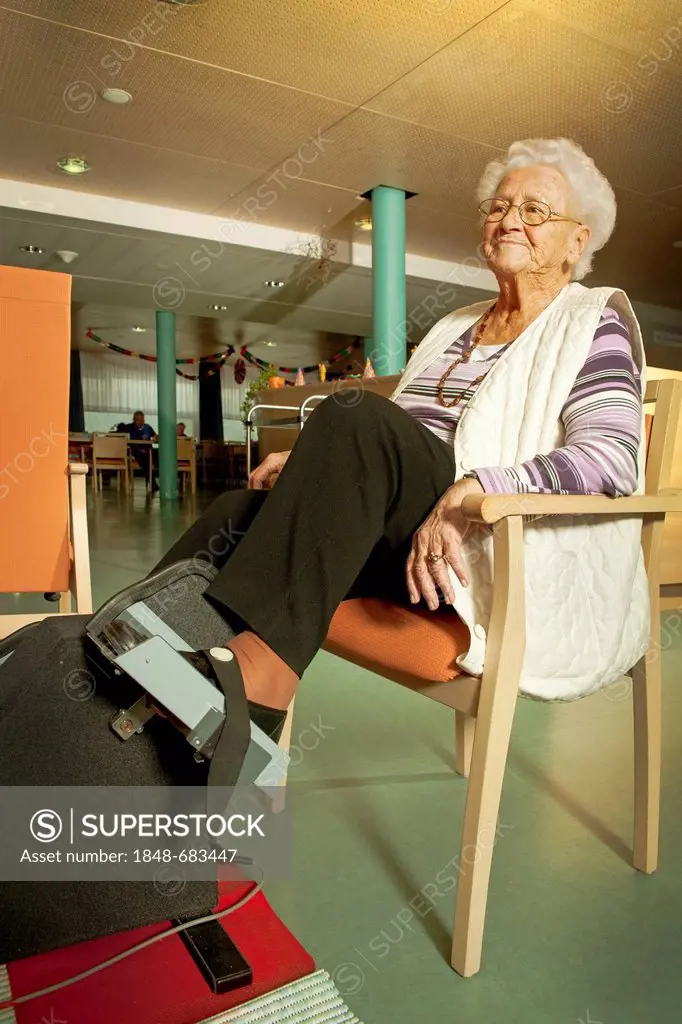 Nursing home, elderly woman exercising with a therapy device