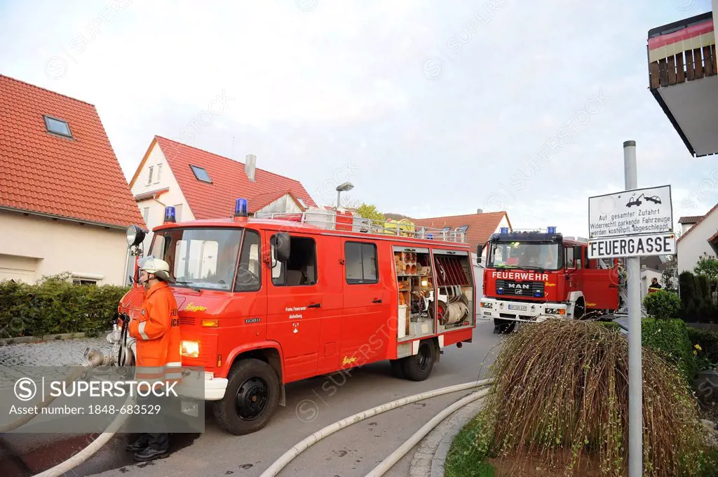 Fire engines during a fire fighting operation at a barn fire next to sign Feuergasse freihalten, German for keep clear path for fire engines, Aichelbe...
