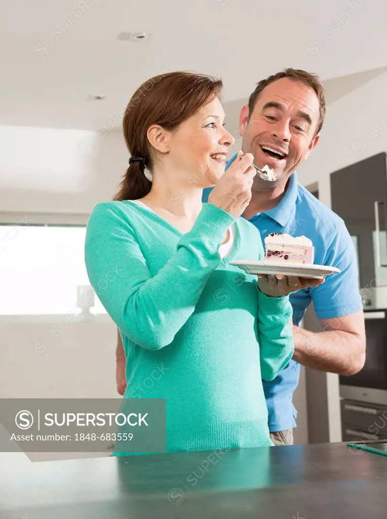 Woman letting a man try a piece of cake