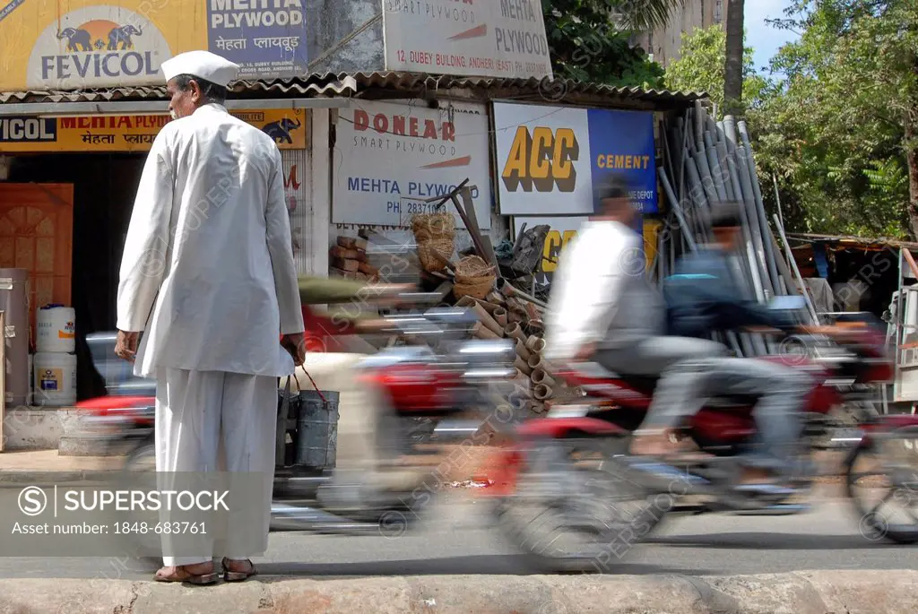 Dabba wallah or food deliverer with Dabbas or food containers crossing a street in Mumbai, India, Asia