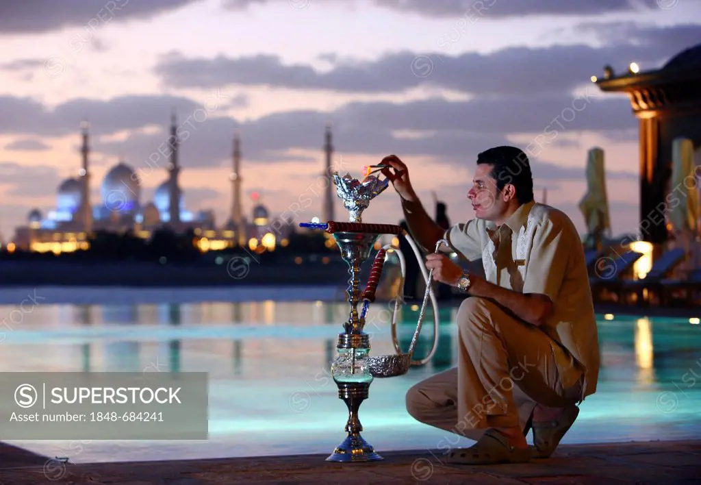 Man with hookah, water pipe, hotel pool, Shangri-La Hotel, Qaryat Al Beri, view on the Sheikh Zayed Mosque, Abu Dhabi, United Arab Emirates, Middle Ea...