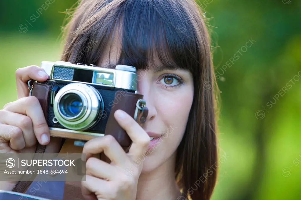 Young woman, 25, holding an old camera
