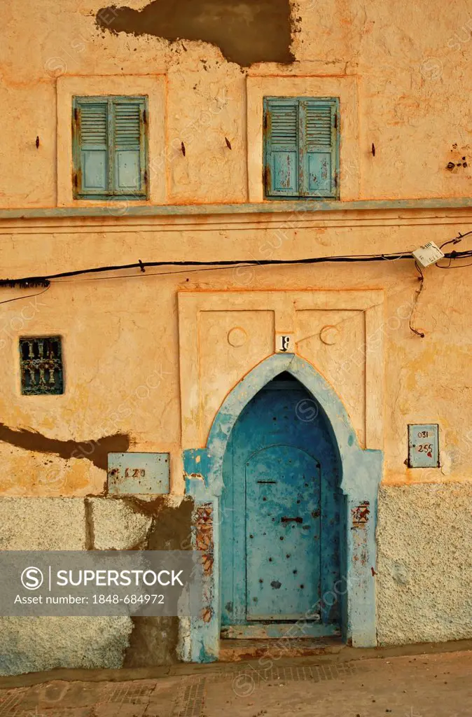 A facade with a typically shaped blue door and blue windows on a white wall in Sidi Ifni, Morocco, Africa