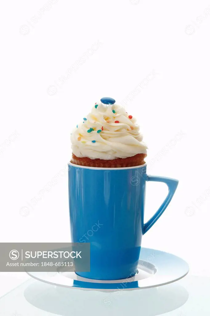 Cupcake with vanilla butter cream in a blue coffee mug