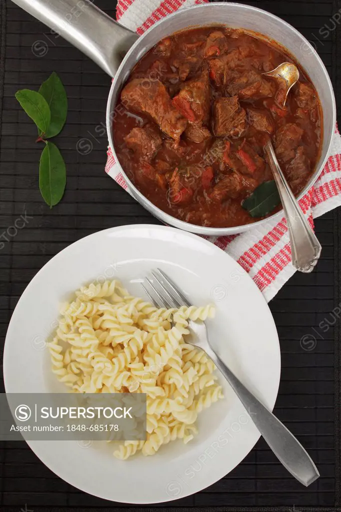 Beef stew or goulash in a pot and noodles