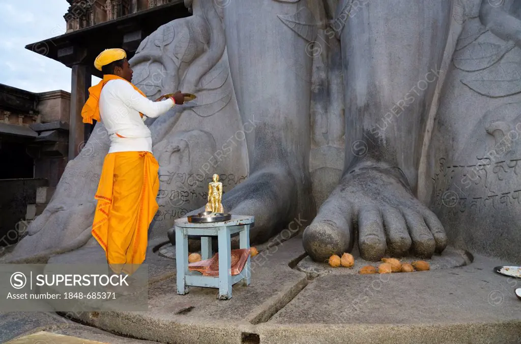 Local priest doing his prayers in front of the statue of Lord Gomateshwara, the tallest monolithic statue in the world, dedicated to Lord Bahubali, ca...