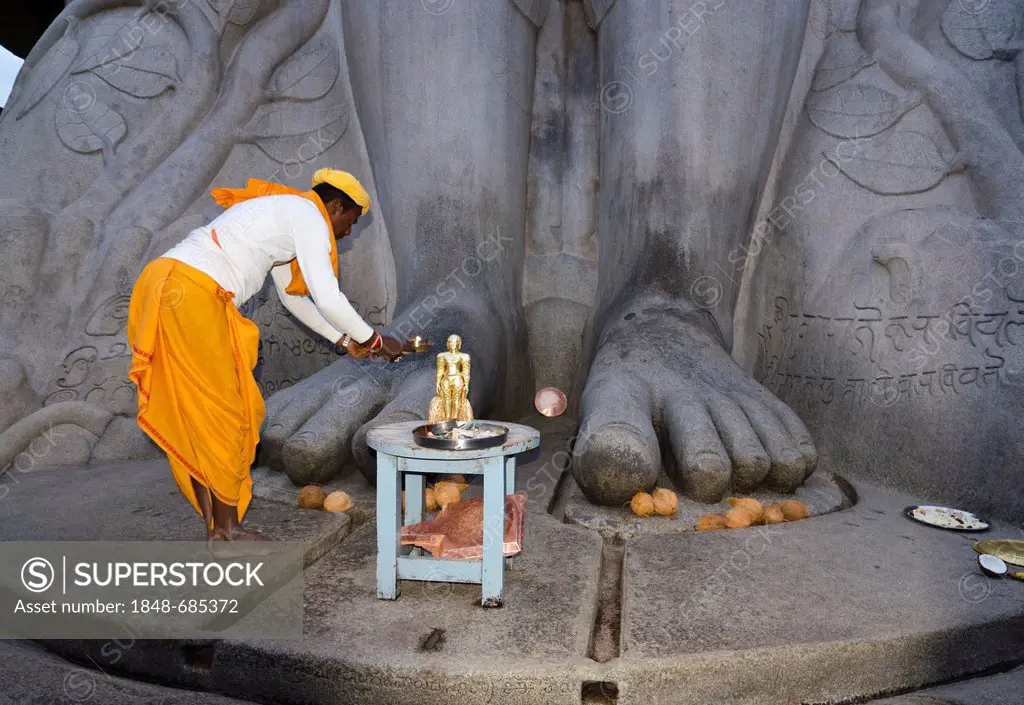 Local priest doing his prayers in front of the statue of Lord Gomateshwara, the tallest monolithic statue in the world, dedicated to Lord Bahubali, ca...