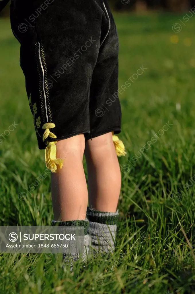 5-year old boy wearing traditional leather pants and dress socks standing in the grass
