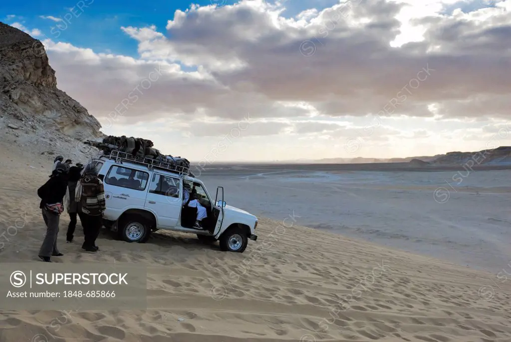 Tourists standing in front of a four wheel drive vehicle, White Desert, Farafra Oasis, Western Desert, Egypt, Africa