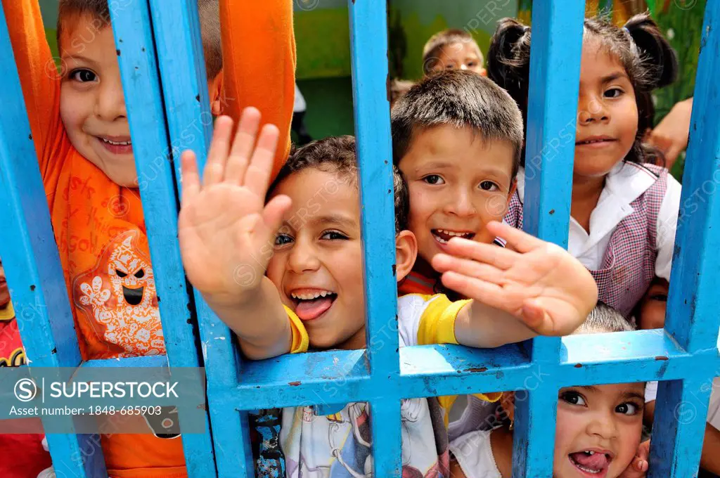 Happy children waving from behind iron bars, Queretaro, Mexico, North America, Latin America