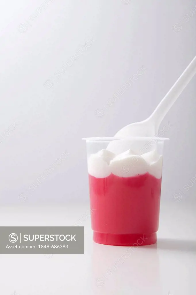 Pink jelly with whipped cream and plastic spoon