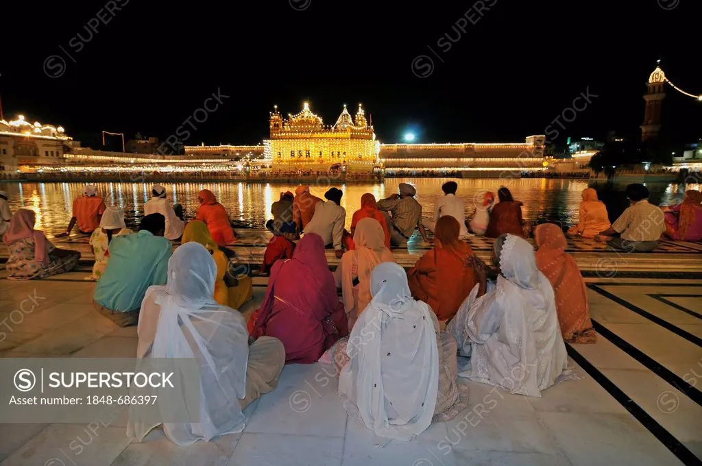 Praying Sikhs in front of the Sikh sanctuary Harmandir Sahib or Golden Temple in the Amrit Sagar, lake of nectar, Amritsar, Punjab, North India, India...