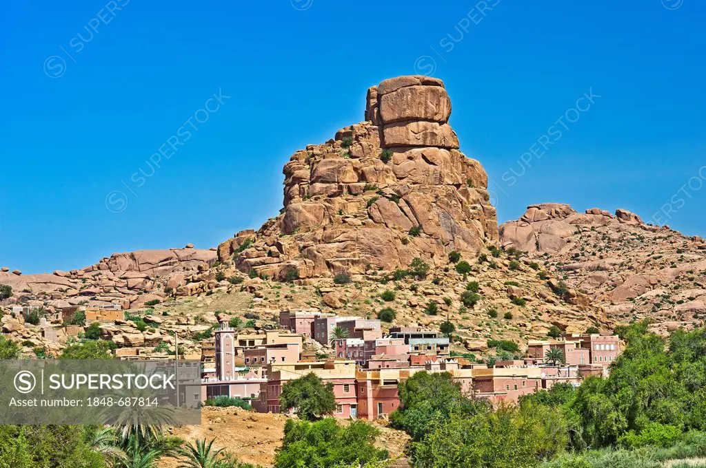 Small village of Aguard Ouda with a mosque in front of the Chapeau Napoleon or Napoleon's hat rock formation, Tafraoute, Anti-Atlas mountain range, so...